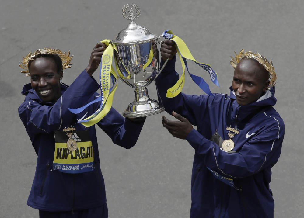 Edna Kiplagat, left and Geoffrey Kirui, both of Kenya, hold a trophy together after their victories in the 121st Boston Marathon on Monday in Boston.