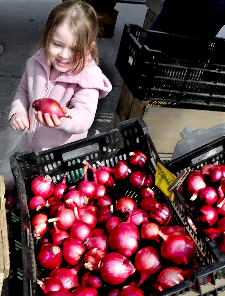 Jacklynn Lee, of Fairfield, seems pleased with her selection of red onions from Snakeroot Organic Farm on the first day of the Downtown Waterville Farmers' Market on The Concourse on April 17, 2014. The farmers market has to move this year to make way for Colby's student residence. The council will vote on whether to close Common Street to create space for the Thursday farmers market's 2017 outdoor season.