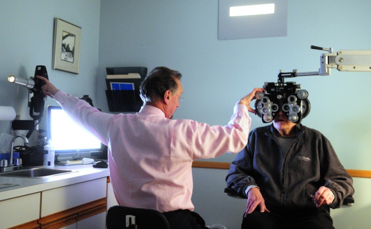 Dr. Kenneth Nuzzo adjusts the projector displaying a test chart and the lens on the phoropter in January while doing an examination of Julie Bernier at his office. Nuzzo, who is retiring, is selling his practice to Vision Care of Maine.