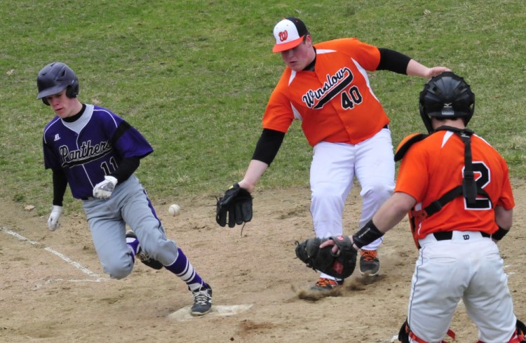 Winslow's Cam Winslow (40) reaches for the ball as Waterville's Jackson Aldrich scores during a game Wednesday in Waterville. Winslow catcher Patrick Hopkins backs up play.