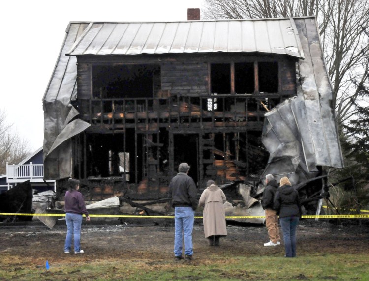 People survey the remains of a home Thursday morning on Main Street in Vassalboro that was destroyed by fire the previous night.