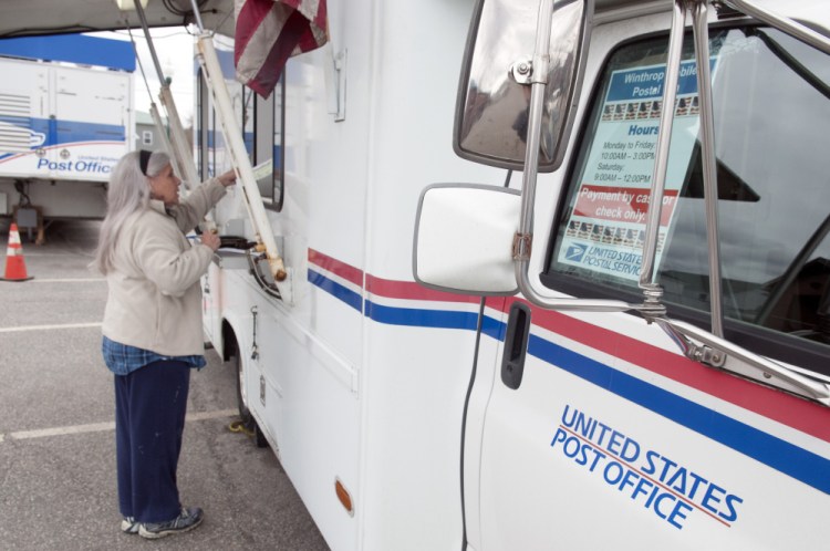 Mary Dyer conducts her postal business Thursday at a mobile post office truck in downtown Winthrop. The truck is set up in the parking lot of the old post office, which burned on Feb. 21.