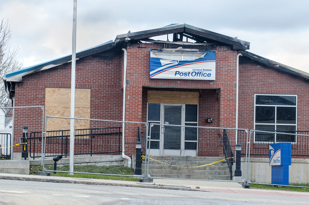 The burned-out Winthrop post office, seen Thursday, is expected to be demolished. A mobile post office truck is conducting U.S. Postal Service business in the back parking lot.