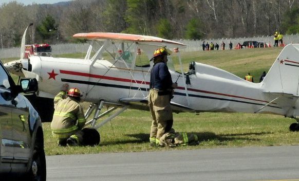 Waterville police and firefighters arrive at the scene of a reported overturned aircraft at the Waterville Airport on Sunday. Police say strong wind caused the bi-plane, piloted by Keith Deschambeault of Rangeley, to partially overturn while landing. Deschambeault was not injured and the plane was damaged. In background are members of statewide fire and rescue departments that were present for unrelated training.