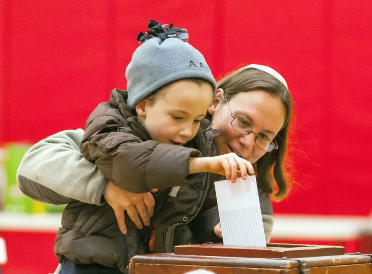 Aaron Asch, 4, drops a bond vote ballot for his mother, Rabbi Erica Asch, just after 8 a.m. Friday in the Hall-Dale Elementary School gymnasium in Hallowell.
