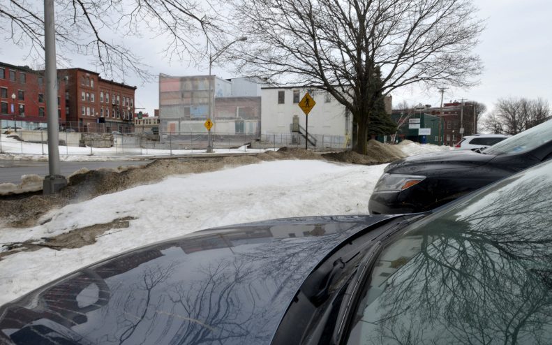 Cars in a proposed parking lot for Colby College sit in front of the empty lot that will soon be home to a boutique hotel on Front Street in Waterville on March 21  Waterville City Council is expected to take a final vote on leasing parking spaces from the city for the hotel Tuesday.