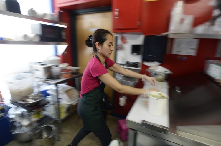 Chau Du prepares an order at Pho Co. in the Public Market House on Thursday. She and her husband, Hoang Nguyen, opened their  food stand in December. Du, says her husband, is "like an artist always working on a new masterpiece."