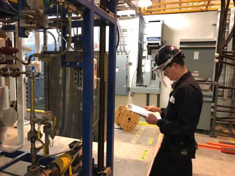 A technician takes a reading from an apparatus that turns wood waste into fuel. The University of Maine and a Massachusetts biotech firm have launched a pilot program in Old Town to prove that their technology can operate on a commercial scale.
