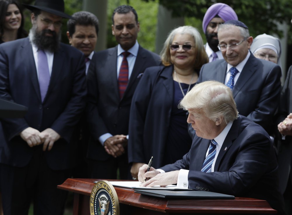 President Trump signs an executive order in the Rose Garden of the of the White House Thursday, directing the Treasury Department not to take "adverse action" over churches or religious organizations for political speech.