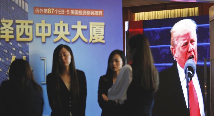 Footage of Donald Trump is shown as workers await investors during an event in Shanghai on Sunday.promoting EB-5 investment in a Kushner development.