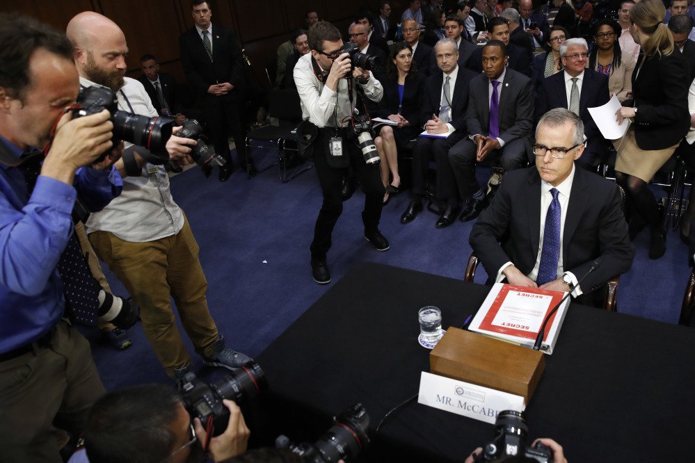 Photographers surround acting FBI Director Andrew McCabe as he takes his seat with a folder marked "Secret," on Capitol Hill in Washington on Thursday before testifying before the Senate Intelligence Committee.