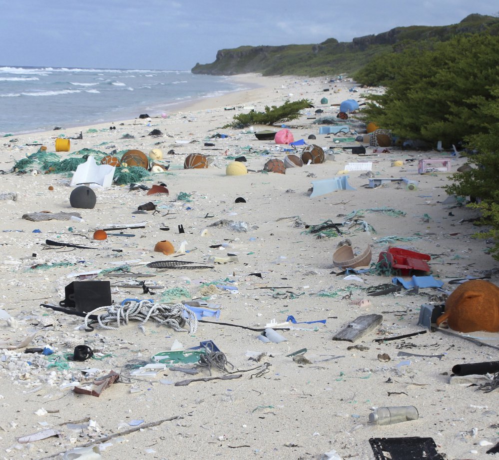 Above, a crab shelters in a piece of plastic debris on the beach of Henderson Island, at left. No humans live on the tiny atoll in the middle of the Pacific Ocean, but scientists say that as of 2015, an estimated 38 million pieces of trash had washed up there, with about 3,500 pieces of trash still arriving on the beaches daily.