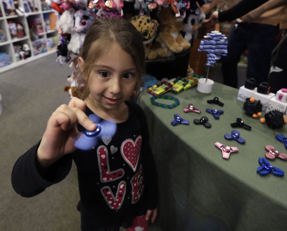 Penelope Daversa, 4, plays with a fidget spinner at the Funky Monkey Toys store in Oxford, Mich. Many stores are having a hard time keeping them in stock and parents are going crazy trying to find them.