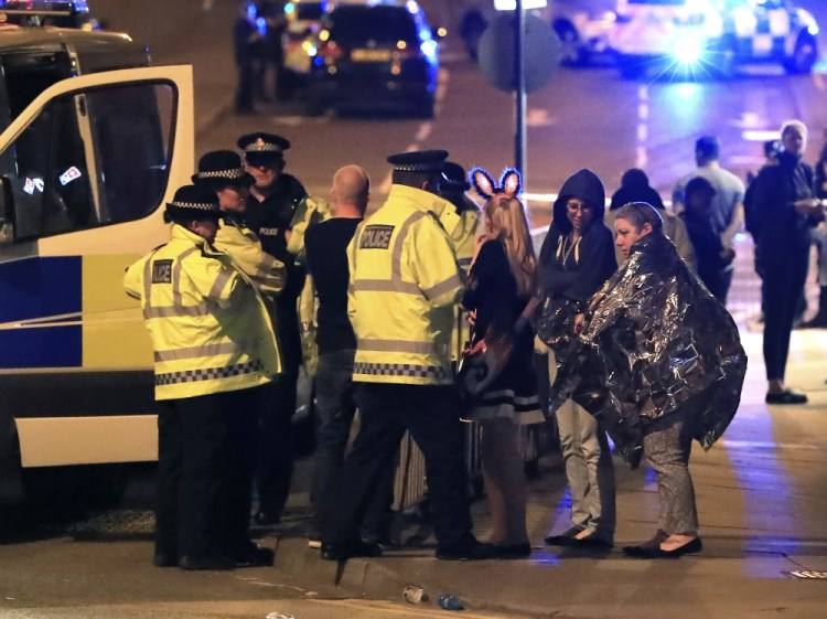 Emergency services personnel speak to people outside Manchester Arena in northern England after an explosion at the venue following an Ariana Grande concert Monday.