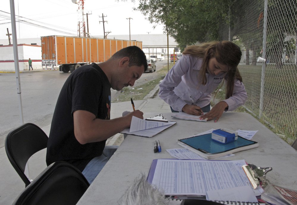 Aimee Gomez, a recruiter for assembly plants in Reynosa, Mexico, helps Juan Luis Alvarado de la Rosa fill out a job application at an industrial park across the border from McAllen, Texas. President Trump has said NAFTA was "a catastrophic trade deal for the United States," but the reality is far more complicated, especially at the border where communities are enmeshed in a shared economy.