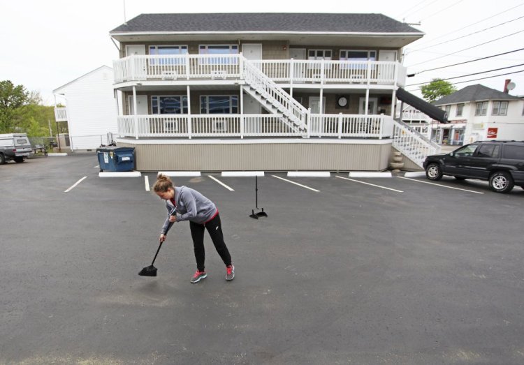 Marija Bralovic, who came from Serbia to work in Maine, sweeps the parking lot at the Green Dolphin Motel in Old Orchard Beach on Thursday in preparation for opening day Friday. Low unemployment and changes to a federal visa program are causing staffing shortages for some of the state’s hospitality businesses.