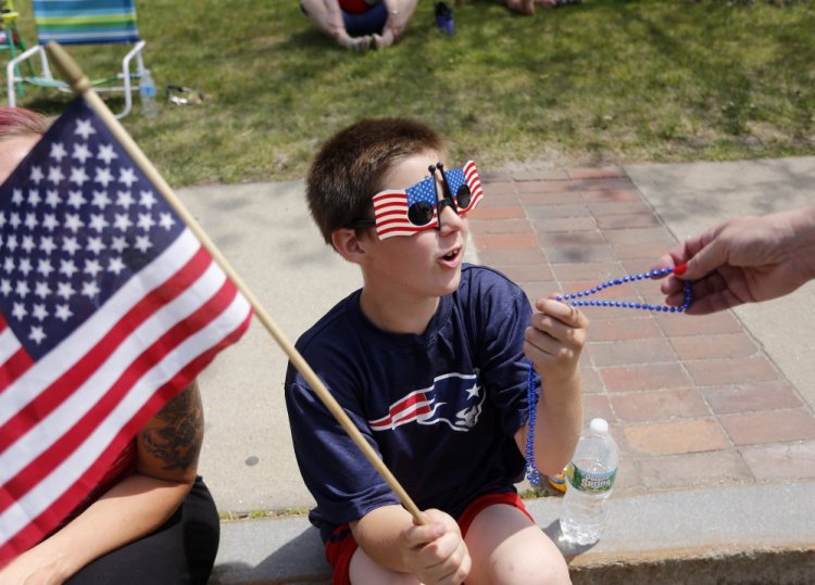 Kevin Woods, 8, of Old Orchard Beach is given beads by a marcher at the Old Orchard Beach Memorial Day parade.