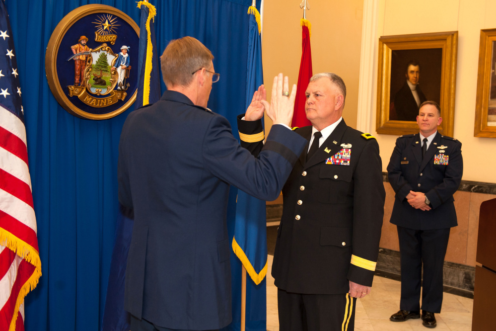 Brig. Gen. Douglas A. Farnham, left, the Adjutant General for the Maine National Guard, administers the oath of office to newly promoted Brig. Gen. Dwaine E. Drummond, center, at the Hall of Flags at the state Capitol immediately following Drummond's promotion to brigadier general. Col. Frank Roy, commander of the 101st Air Refueling Wing in Bangor, acting as master of ceremonies for the day, in back.