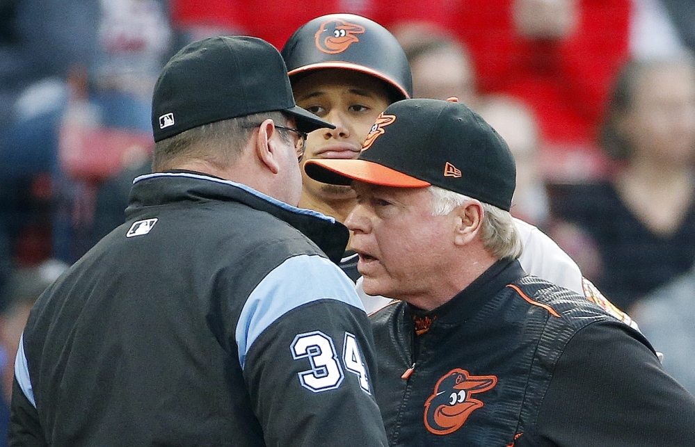 Baltimore Orioles manager Buck Showalter, right, talks with first base umpire Sam Holbrook as Manny Machado looks on during the first inning of a game Tuesday in Boston.