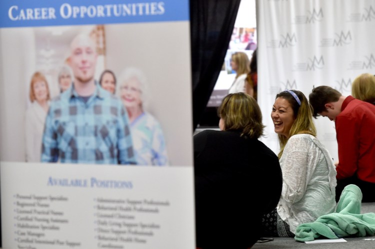 Jennifer-Lee Hesseltine, right, laughs as she talks with Kaitlin Taylor and they fill out job applications at the Growth Council job fair at the T&B Celebration Center in Waterville.