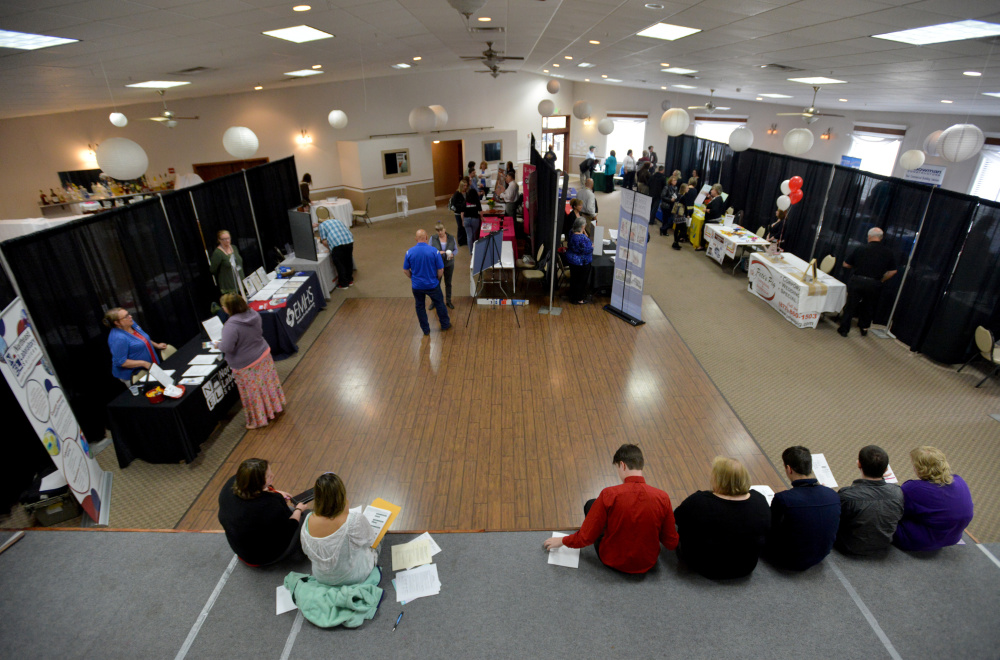 Job seekers sit on the stage filling out job applications Friday at the Growth Council job fair at the T&B Celebration Center in Waterville.