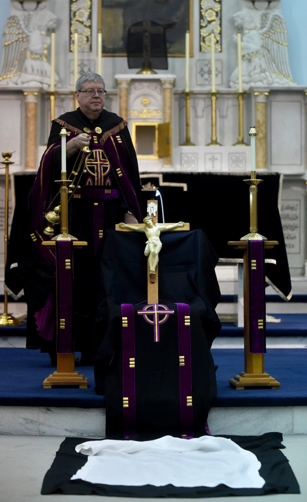 Father Larry Jensen holds the figure of Jesus used in the Good Friday rite where communicants kiss the feet at St. Joseph's Maronite Church in Waterville on April 14. Jensen has been relieved of his priestly duties amid allegations of sexual abuse 15 years ago in Connecticut.