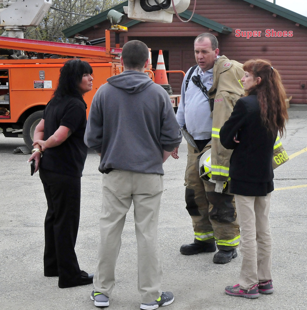 Waterville firefighter John Gromek speaks on Tuesday with Super Shoes store employees, from left, Nicole Witham, manager Wayne Ireland and Rebecca Leonard outside the Waterville store as firefighters extinguish a smoky fire there.