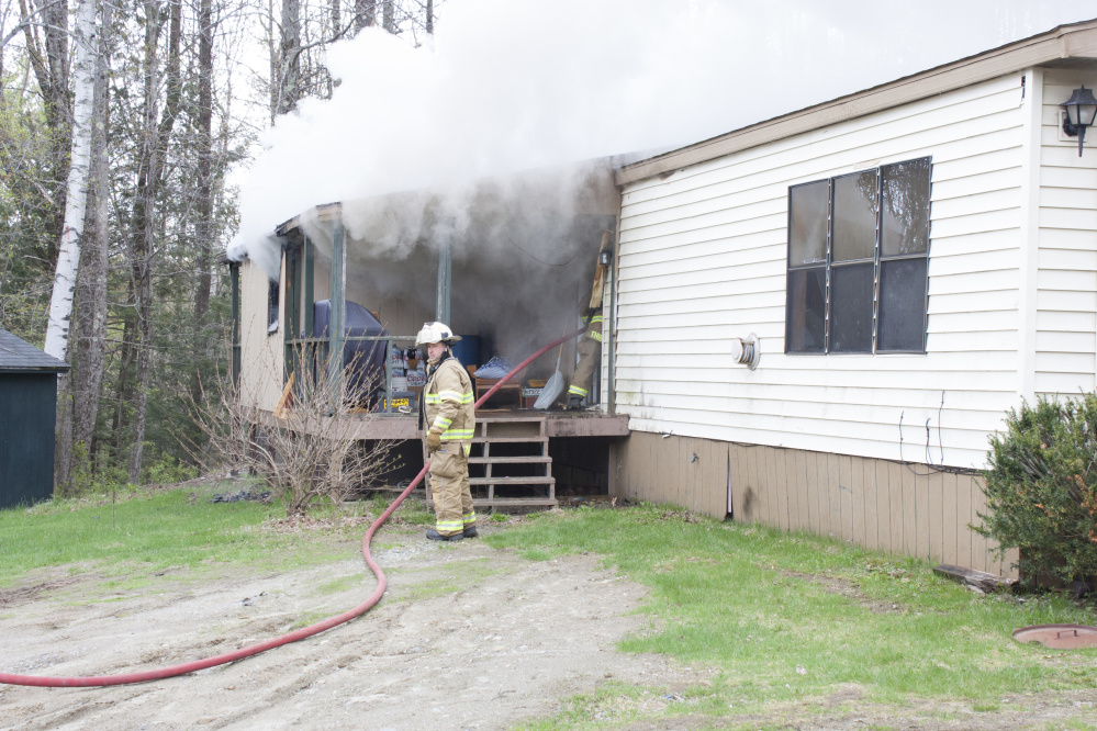 A firefighter works to put out a fire Wednesday morning at 905 Smithfield Road in Belgrade.