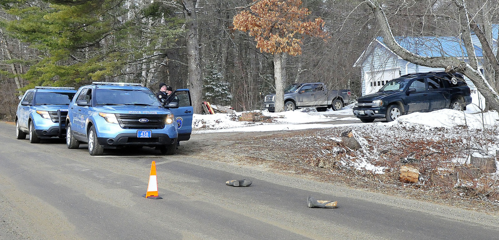 Two Maine State Troopers consult outside a home on the Winnecook Road in Burnham while investigating the reported death of a woman on April 2. A pair of winter boots lie in the roadway in foreground.