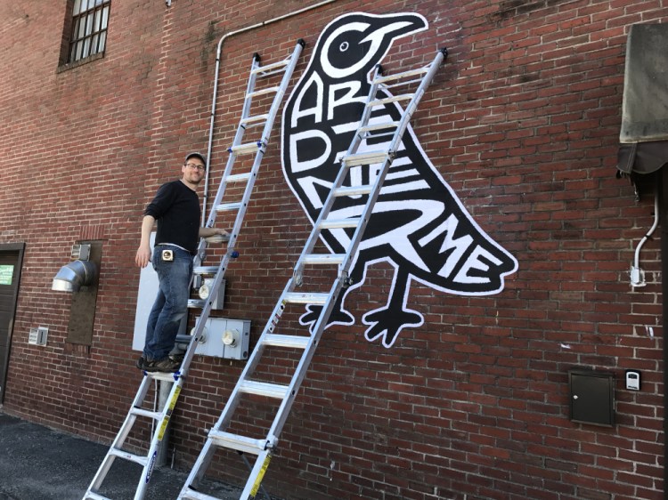 Scott King takes a short break from putting up his contribution to the 10th annual Variations exhibition in Gardiner in this recent photo. Each of the images are rendered in paper and applied to the back of Water Street buildings with wheat paste.