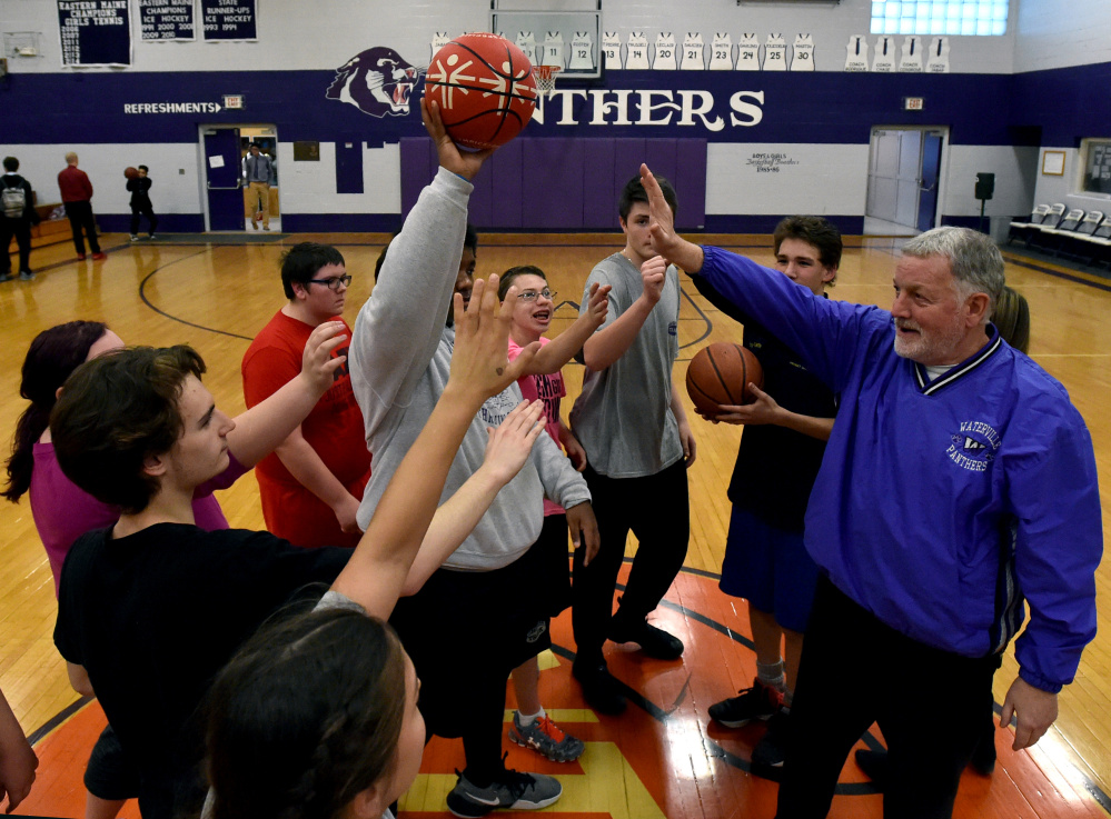 Waterville unified basketball coach Ken Lindlof, right, head calls his players into a circle for a pep talk before running drills during a practice last season.