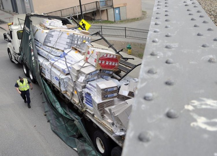 State Trooper Shawn Porter examines a tractor-trailer that struck the trestle on May 5, 2015 on Water Street in Augusta. The accident that occurred at 8:45 a.m. ripped apart the trailer but no injuries were reported, according to Augusta Police Lt. Kevin Lully. Traffic was down to one lane as the contents of the damaged trailer were moved to enable the truck to be towed away. Augusta and State Police are investigating the accident, according to Lully.