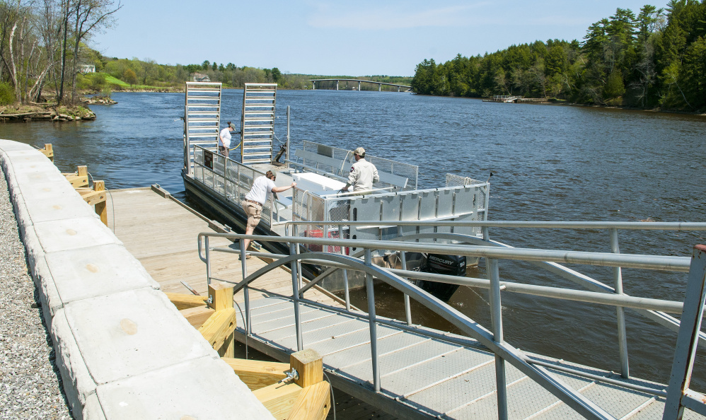 Swan Island staffers push the ferry off from the new dock Wednesday on the shore of Kennebec River in Richmond.