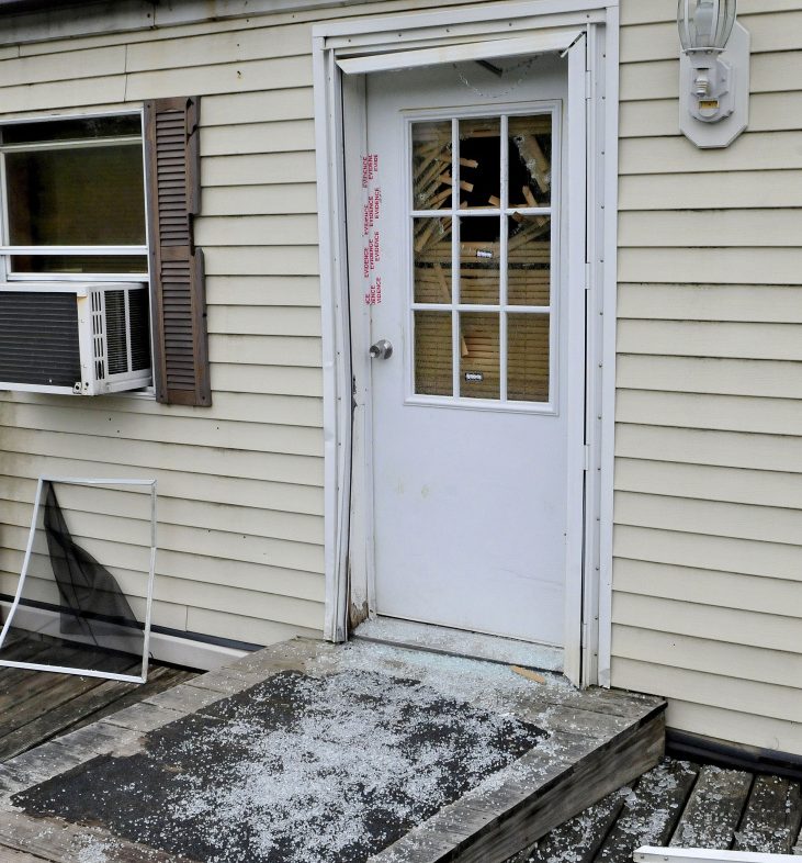 Glass from a shattered window in a door that is sealed with police evidence tape is seen at the front entrance to a mobile home at 1003 Oakland Road in Belgrade on Monday. Homeowner Roger Bubar died in a police officer-related shooting over the weekend and his son, Scott Bubar, was wounded.
