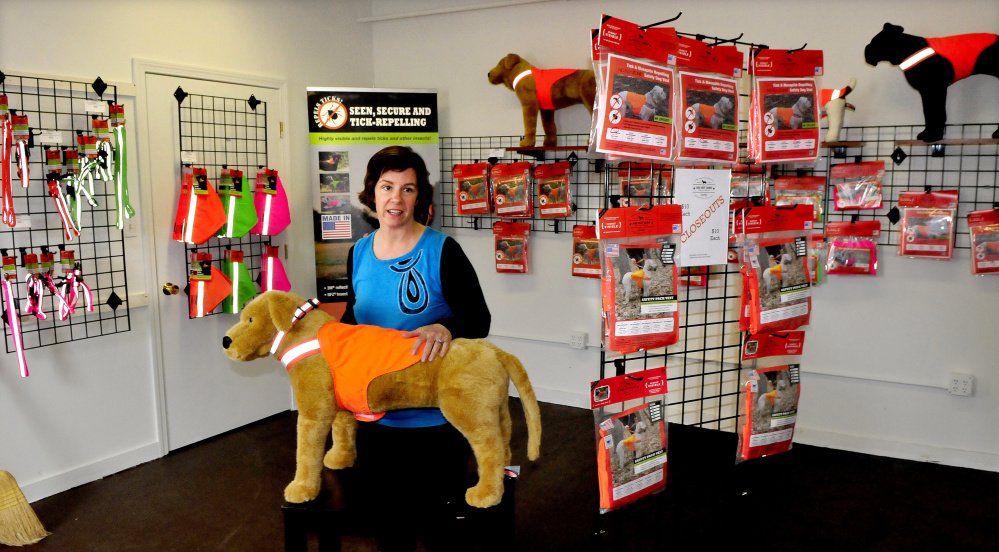 Owner Julie Swain fits a safety vest on a dog mannequin Wednesday beside many products sold at the new Dog Not Gone factory outlet store inside the Maine Stitching Specialties company in Skowhegan.