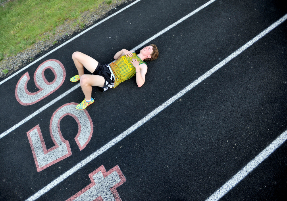 Winslow's Ben Smith gets some rest on the track during practice Wednesday at the high school.