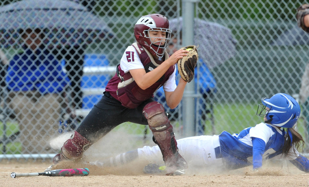 Monmouth Academy catcher Abby Ferland (21) gets the force out at home as Madison Area Memorial High School's Emily Edgerly (8) slides in too late in Madison on Thursday.