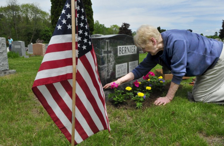 Dorothy Bernier, of Waterville, plants flowers Wednesday around the grave of her husband, Joseph, who was wounded while serving in the U.S. Marines, at St. Francis Catholic Cemetery in Waterville.