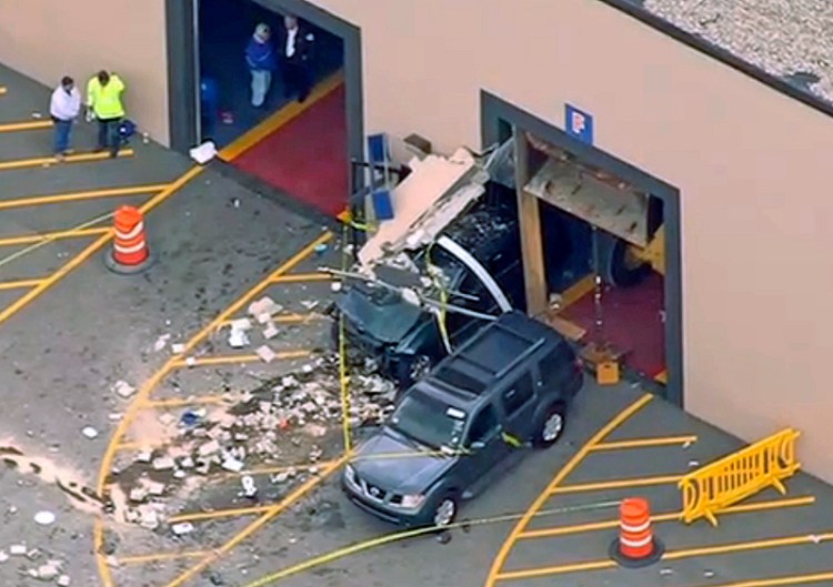 This image from video provided by NBC Boston shows the crash scene Wednesday after a vehicle suddenly accelerated at an auto auction and struck several people before it going through a wall of the building in Billerica, Mass. 