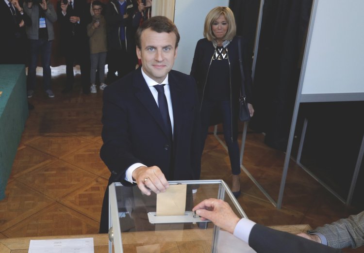 Emmanuel Macron casts his ballot at a polling station while his wife, Brigitte, looks on during the the second round of the 2017 French presidential election on Sunday.