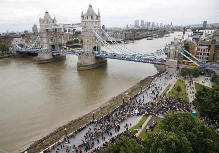 People attend a vigil for victims of Saturday's attack on London Bridge, at Potter's Field Park with Tower Bridge in the background in London, on Monday.