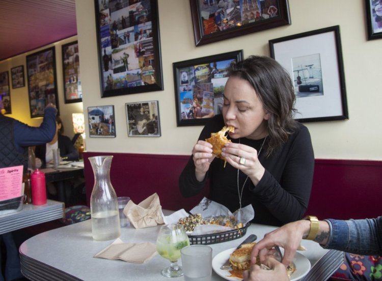 Vanessa Helmick feasts on a Vegan Meltaway, a vegan grilled cheese filled with tomatoes and caramelized onions at Silly's in Portland.