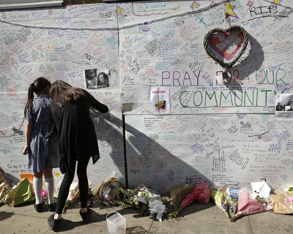 People write messages on a wall for the victims and in support of those affected by the massive fire in the Grenfell Tower in London on Thursday. At least 17 people died.