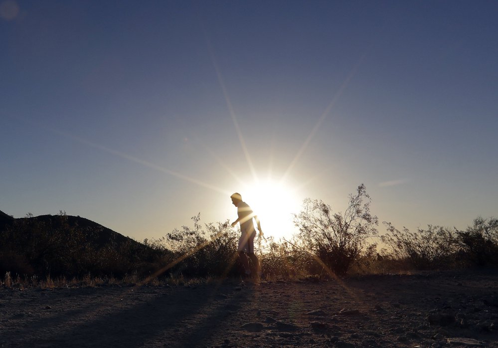 A man runs through South Mountain Park in Phoenix at sunrise to avoid the excessive heat Friday. A record heat wave is rolling into Arizona, Nevada and California.