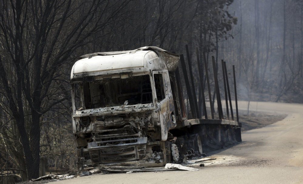 A burnt truck lies on a dirt road between Castanheira de Pera and Figueiro dos Vinhos in central Portugal on Sunday. Forest fires killed at least 61 people, many of them trapped in their cars as flames swept over a road.