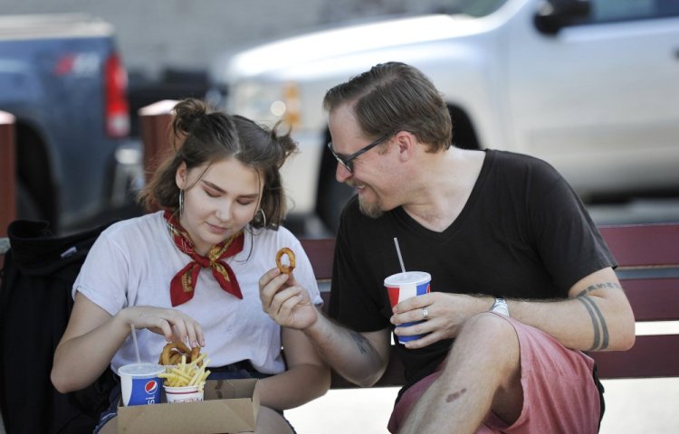 Joshua Bodwell, who first tasted fast food in the mid-1970s at Rapid Ray's in Saco, enjoys fries and onion rings there with his daughter Elona, 14, on Monday.