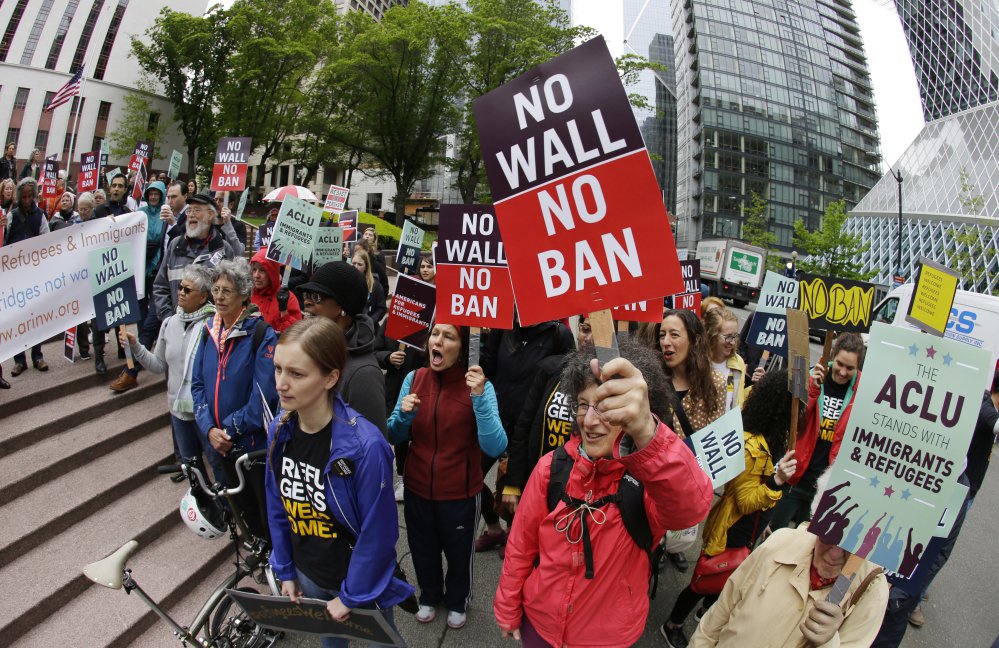 Protesters wave signs and chant during a May demonstration against President Trump's revised travel ban, outside a federal courthouse in Seattle. The Supreme Court is letting the Trump administration enforce its 90-day ban on travelers from six mostly Muslim countries, overturning lower court orders that blocked it.