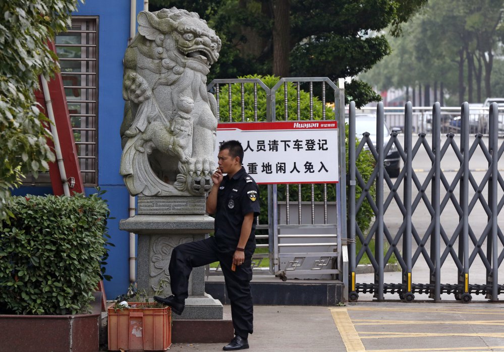 A security guard smokes near a main entrance gate of the Ganzhou Huajian International Shoe City Co.'s factory, which has made shoes for the brand owned by Ivanka Trump, left. The firm, located in Ganzhou, has denied abuse allegations, and Trump has not replied to a letter from China Labor Watch..