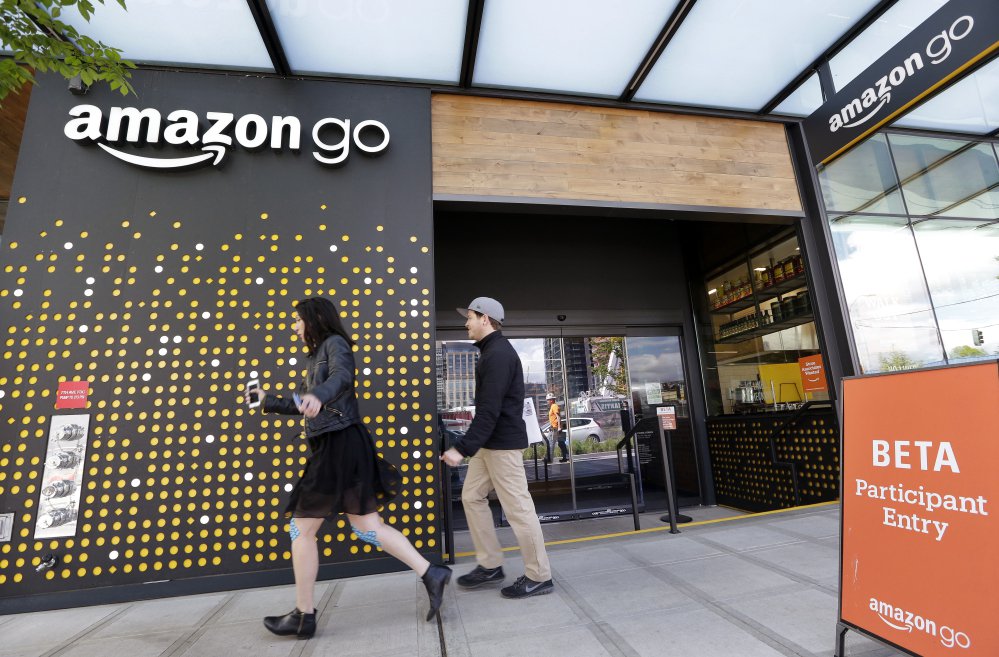 People walk past an Amazon Go store, currently open only to Amazon employees, in Seattle. Amazon wants to sell Amazon and Whole Foods shoppers alike even more goods and services, including stuff they might not even realize they need.