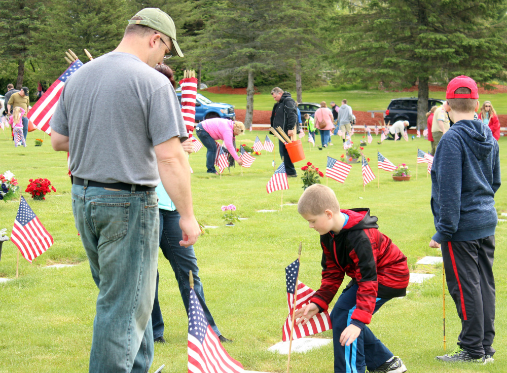 Derek Fennell, a Marine Veteran, with sons Kamren, center, and Evan placed flags Saturday at the VA Cemetery in Augusta in honor of those who have served our country.